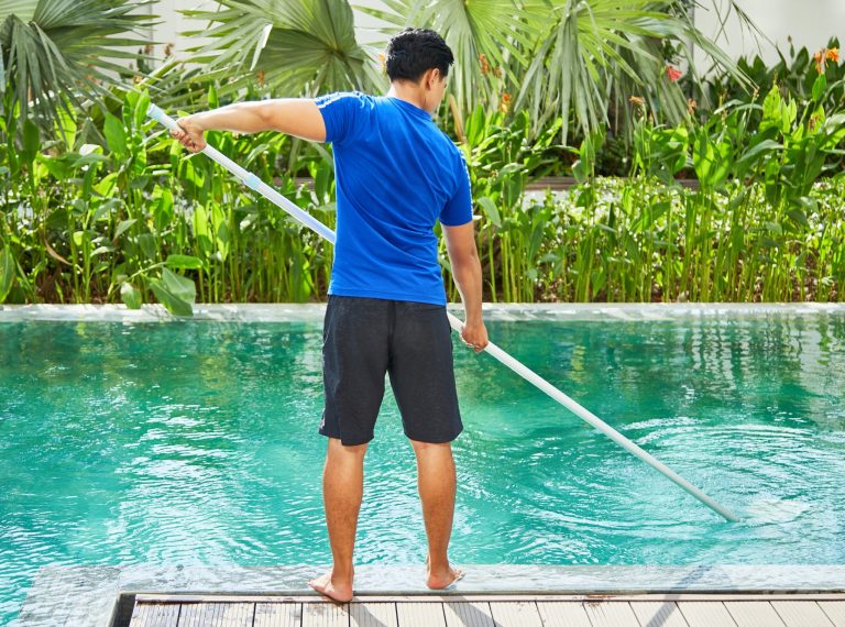 Young man cleaning pool